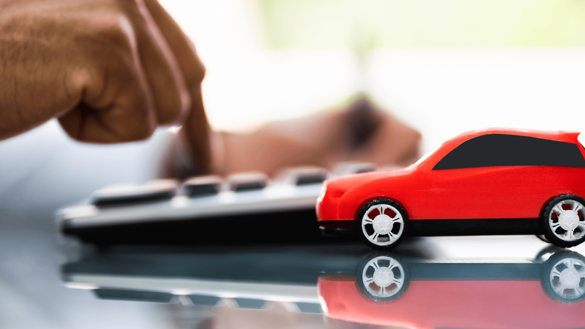 red car next to fingers on calculator